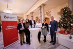 Eine Gruppe von sechs Personen hält Zertifikate in der Hand und steht neben einem Weihnachtsbaum.