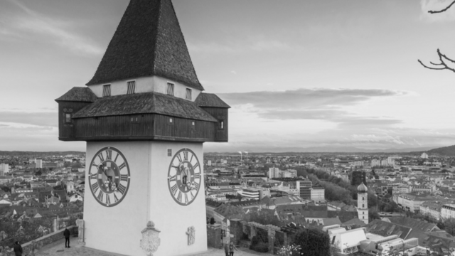 Uhrturm auf einem Hügel mit Stadtansicht im Hintergrund, in schwarz-weiß.