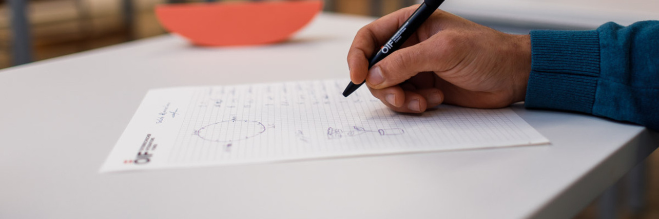 Eine Hand hält einen Stift und schreibt auf einem Block