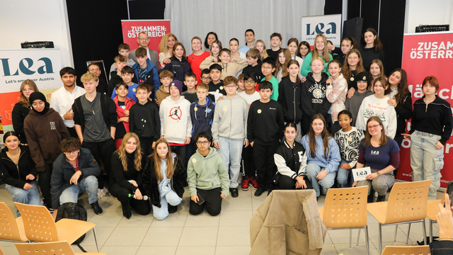 Gruppenfoto von Jugendlichen und Erwachsenen bei einer Veranstaltung, im Hintergrund Banner mit den Texten „Zusammen: Österreich“ und „Lea“.