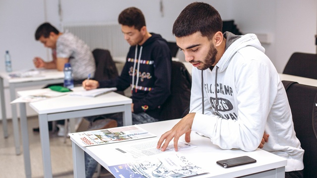 Gruppe von Männern sitzt in einem Deutschkurs.