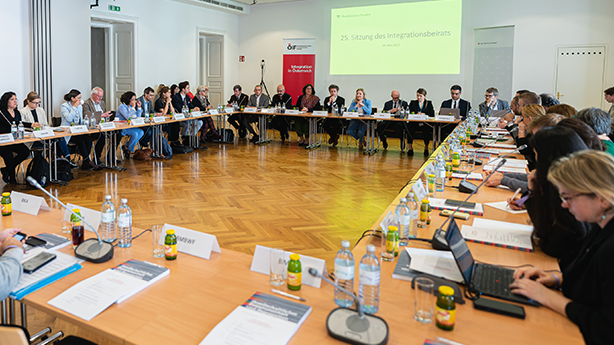 Besprechung des Integrationsbeirats mit Teilnehmern an einem großen Tisch in einem Konferenzraum.