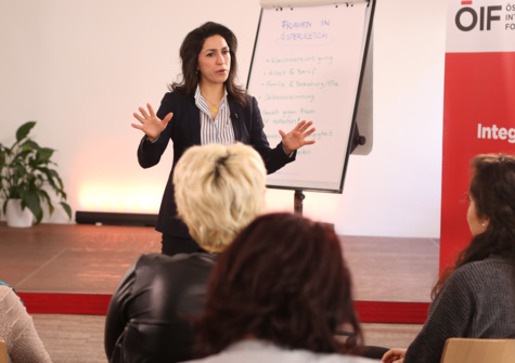 Eine Vortragende erklärt das Thema „Integration in Österreich“ vor einem Publikum.